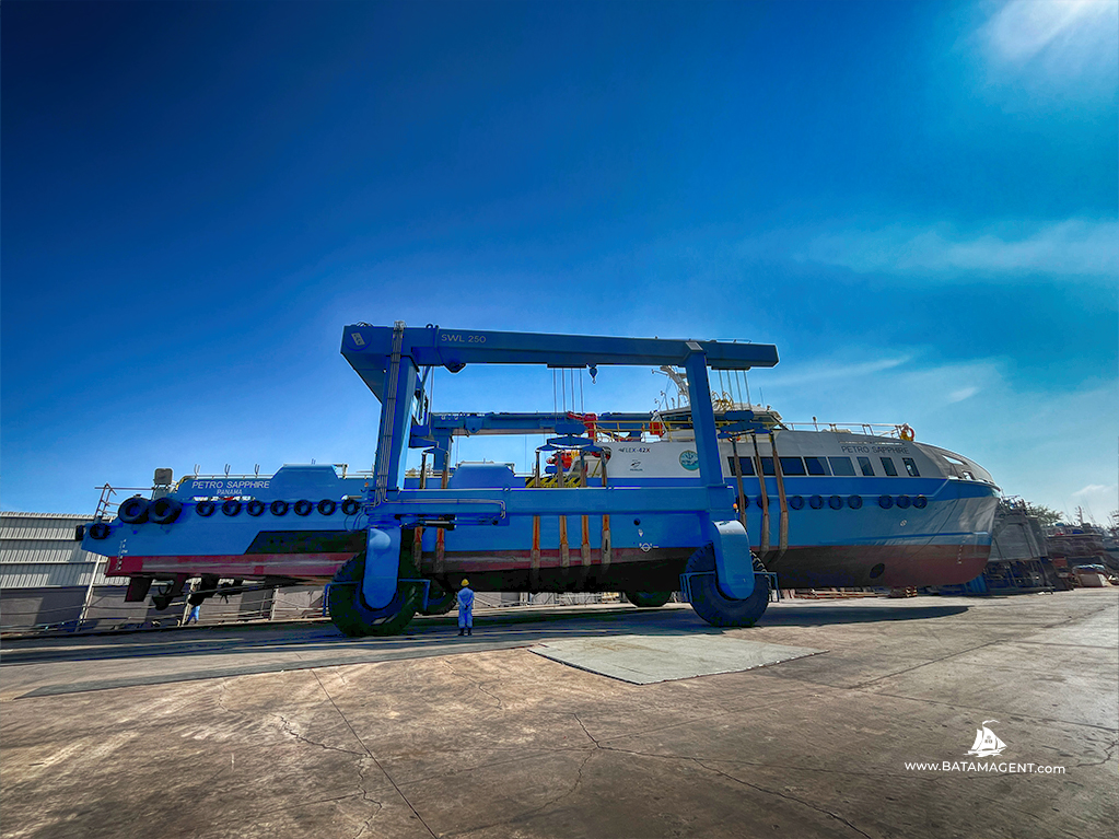 Wide view of mobile boat hoist lifting Fast Crew Boat Petro Saphire at Batam shipyard Indonesia