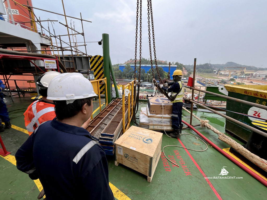 Vessel crew handling delivered ship spares onboard MV ANASSA in Batam.