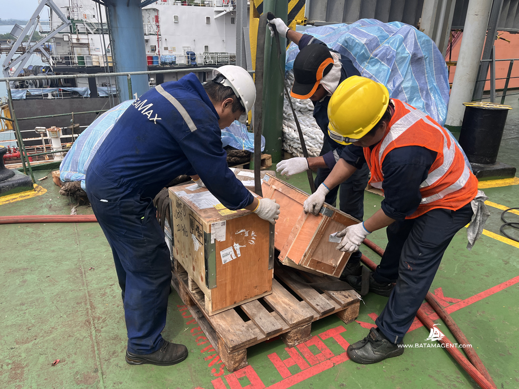 Crew members handling ship spares onboard MV ANASSA during her shipyard stay in Batam.